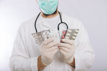 Doctor's hands in white gloves hold pills close-up. Types of drugs. Medical worker in a white coat