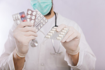 Doctor's hands in white gloves hold pills close-up. Types of drugs. Medical worker in a white coat