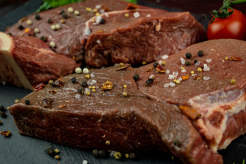 Two mouth-watering chunks of fresh juicy meat with seasoning on a slate black tray.