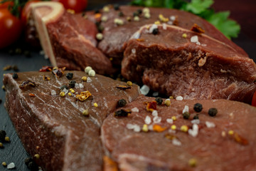 Two mouth-watering chunks of fresh juicy meat with seasoning on a slate black tray.