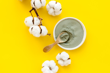 Blue cosmetic clay - face and body skin care - on yellow background top-down