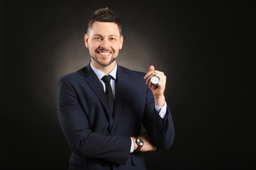 Businessman with watch and clock on dark background. Time management concept