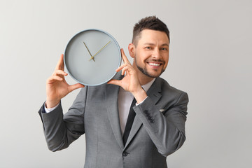 Businessman with clock on light background. Time management concept