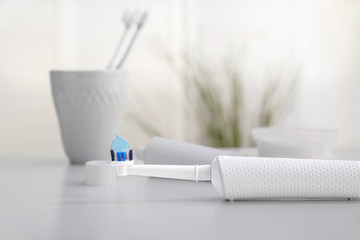 Electric tooth brush with paste on table in bathroom