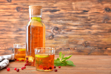Bottle and glasses of tasty cold tea on table