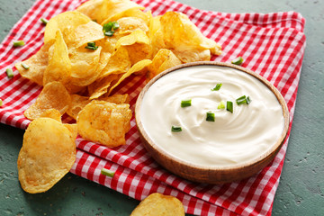 Tasty sour cream and potato chips on table