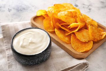Tasty sour cream and potato chips on table