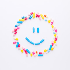 Happy face made of pills on white background
