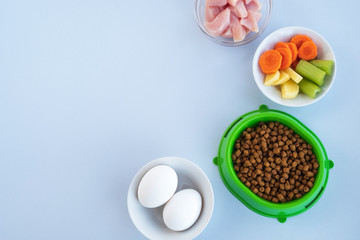 Pet food and ingredients of natural products on light background. Healthy diet for pets. Top view, flat lay, copy space