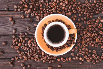 Cup of hot coffee and beans on wooden background