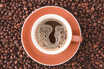 Cup of hot coffee and beans on table