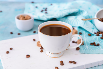 Cup of hot coffee and beans on table
