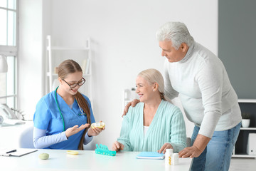 Obraz premium Doctor giving pills to senior couple in clinic