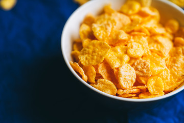 Tasty crispy corn flakes in bowl on the rustic background. Selective focus. Shallow depth of field.