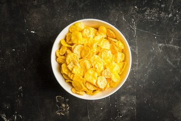 Tasty crispy corn flakes in bowl on the rustic background. Selective focus. Shallow depth of field.