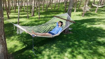 happy Woman Relaxing in a Hammock in a Green Forest .Summer Vacation Concept 