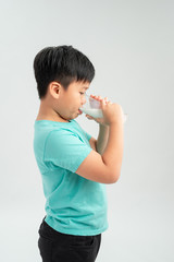 Adorable little boy with glass of milk on white background