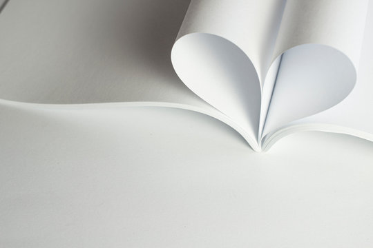 Empty opened magazine and two blank pages that becomes one heart shape. Clean photo of catalog on white background and free space at the bottom as concept for valentines day, love stories etc.