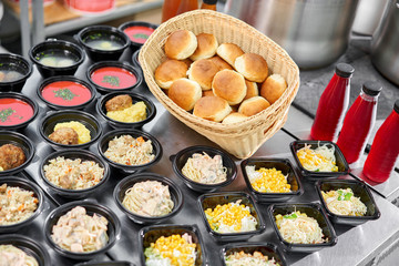 Food delivery. Different in plastic disposable lunch box with healthy natural food. Chicken broth, mashed soup, mashed potatoes with cutlet, seafood pasta, salads, pilaf with a fresh bun.