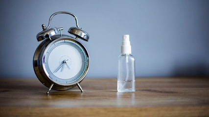 table clock on a wooden nightstand on a gray background in the room with antiseptic