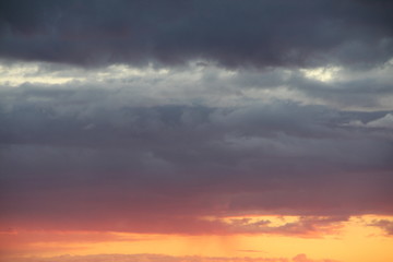 Clouds in the blue sky at sunset or dawn backlit by the sun. Place for text and design.
