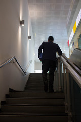evocative image of a businessman who climbs the stairs in an airport