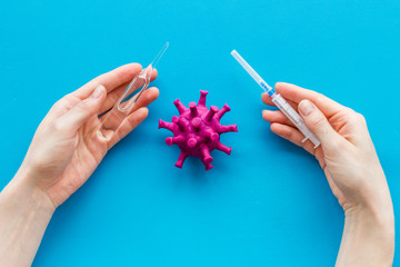 Corona virus Covid-19 - creating vaccine concept, with syringe and hands - on blue background top-down