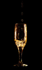 A glass of golden water is isolated on a black .