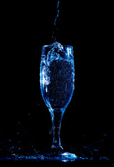 Splashes and drops of water in a glass are isolated on a black background.