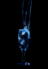 Splashes and drops of water in a glass are isolated on a black background.
