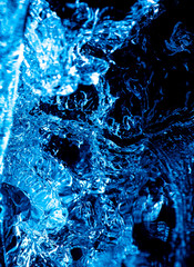 Splashes and drops of blue water on a black .