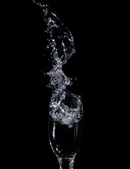 Splashes and drops of water in a glass are isolated on a black .