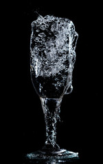 Splashes and drops of water in a glass are isolated on a black .