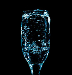 Splashes and drops of water in a glass are isolated on a black background.