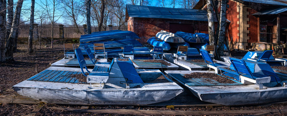 Fototapeta na wymiar Inverted walking boats for wintering in the park. winter boat storage. Stacked up rowboats of a boat hire in winter