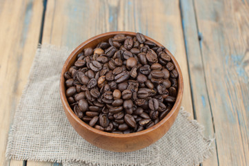 Dark coffee beans in a wooden bowl. Close up. Copy space.