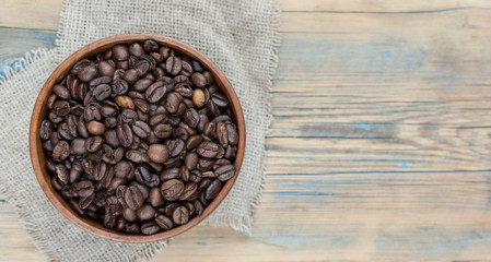Obraz na płótnie Canvas Dark coffee beans in a wooden bowl. Close up. Copy space.