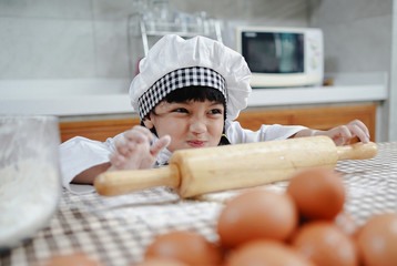 Asian kid child girl enjoys cooking in the kitchen. Happy Asian kids are preparing the dough, bake bakery in the kitchen.