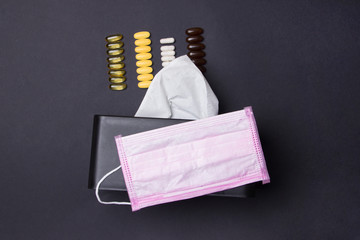 tablets, medical facemask and box with napkins on black colored paper background