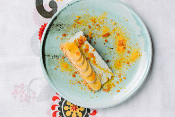 A piece of cream cake with bananas served on a blue plate. Sweet sugary cream dessert. Fruit cake pie.