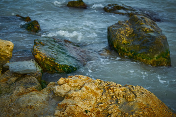 Fototapeta na wymiar Rocky seashore. Sea waves roll over stones.