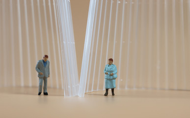 Miniature people separated by transparent walls. The concept of social distance setting.