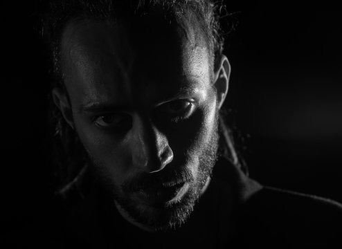 Dramatic portrait of male person looking at camera on dark background