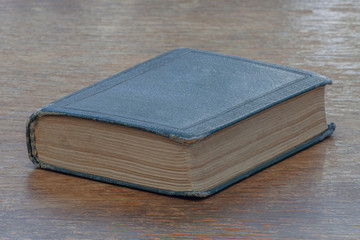 An old shabby book lies on an old shabby wooden table.