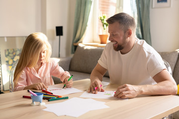 Cute little pre-elementary schoolgirl and her father drawing together at home