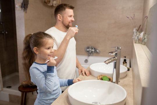 Little girl and her happy father with toothbrushes going to brush teeth