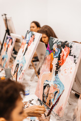 Young women paint with brushes on easels in art class. art school, creativity and people concept