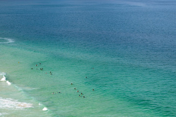 A group of surfers waiting for a wave in the clear ocean - 334371050