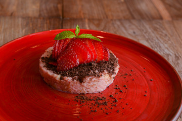 Fruit strawberry dessert with cream, strawberry delicious dessert served on red palte over rustic wooden table.