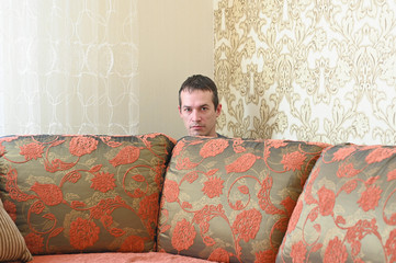 Self-Isolation during coronavirus quarantine. Man in protective mask on the sofa. Covid-19 spread...